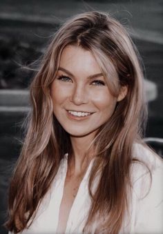 a woman with long hair smiling at the camera