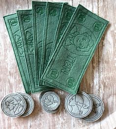 five green towels sitting next to each other on top of a wooden table with coins