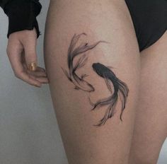 a woman's thigh with a black and white koi fish tattoo on it