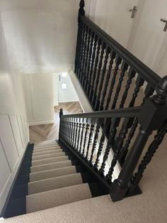 a staircase with black railings and carpeted flooring next to white walls in a home