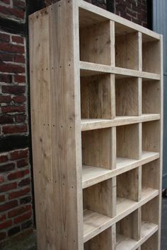 a wooden bookcase sitting next to a brick wall in front of a building on the sidewalk