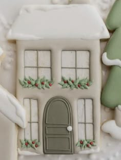 a cookie decorated like a house with holly wreaths on the door and window sill