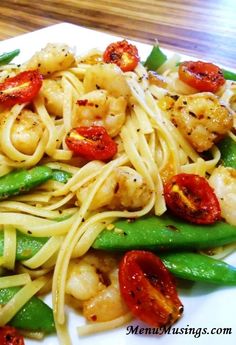 pasta with shrimp, green beans and tomatoes on a white plate