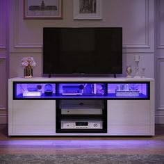 an entertainment center with purple lighting in front of a flat screen tv