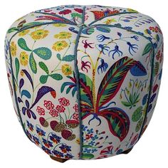 an ottoman with colorful flowers and leaves on the top, sitting in front of a white background