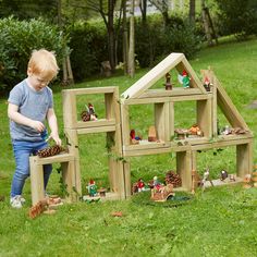 a little boy playing with wooden toys in the grass