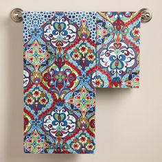 two colorful towels hanging on the wall next to each other, one with an ornate design