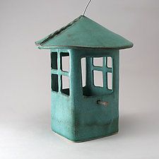 a green birdhouse with a door and window on the outside, sitting on a white surface