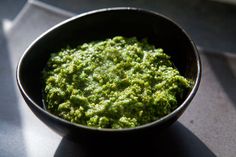 a black bowl filled with green food on top of a table