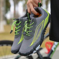 a person holding onto a pair of shoes with neon green laces