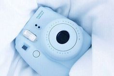 a camera is laying on top of a white sheet in the middle of someone's bed