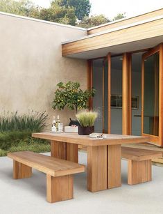 a wooden table and bench in front of a house