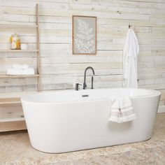 a white bath tub sitting in a bathroom next to a wooden shelf with towels on it