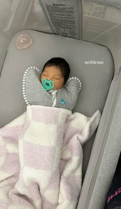 a baby sleeping in a car seat with a pacifier on it's mouth