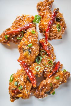 chicken wings with chili and green onions on a white plate