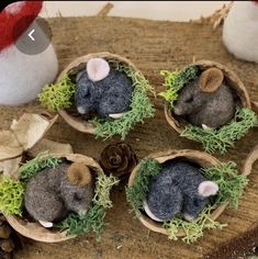 four small stuffed animals are in tiny baskets with moss and pine cones on the table