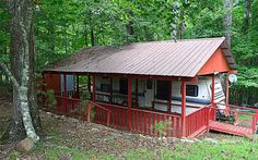 a small red cabin in the woods near trees