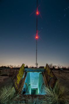 a red traffic light sitting on top of a metal structure in the middle of nowhere