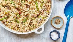 a casserole dish filled with rice, mushrooms and asparagus next to a spoon