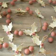 some red berries and white leaves are arranged on a wooden table with brown string around them