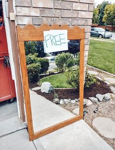 a mirror sitting on the side of a building with a free sign attached to it