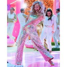 a woman dancing on the dance floor with other people in white and pink outfits behind her