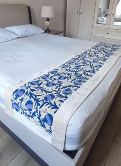 a white bed with blue and white bedspread