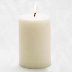 a lit candle on a white background with no one in the photo looking at it