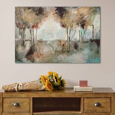 a painting hanging on the wall above a wooden table with flowers in front of it