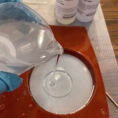 a person in blue gloves pours water into a bowl on top of a table