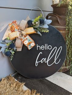 a sign that says hello fall hanging on the side of a house with a bow