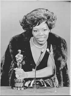 an old black and white photo of a woman holding a trophy