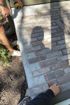 two men are working on a brick walkway