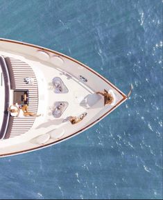 people are sitting on the deck of a boat in the blue water, looking out over the ocean