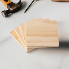 four wooden coasters sitting on top of a table next to scissors and pliers