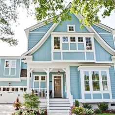 a blue house with white trim and flowers in front