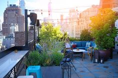 an outdoor seating area on the roof of a building with city skyline in the background