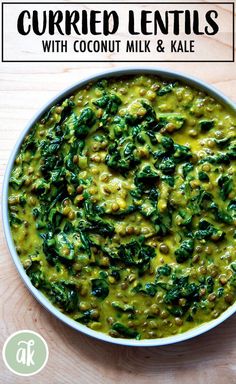 a white bowl filled with spinach and other food on top of a wooden table