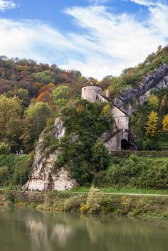 an old castle sitting on the side of a mountain next to a body of water