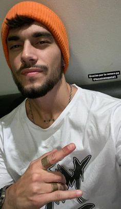 a man wearing an orange beanie and pointing at the camera with his finger in front of him