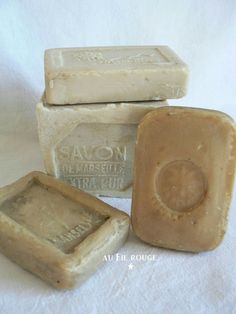 three soap bars sitting next to each other on top of a white cloth covered table