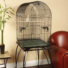 a large bird cage sitting on top of a table next to a red leather chair