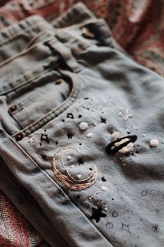 a pair of blue jeans with holes and stars on them sitting on top of a bed