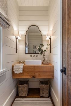 a bathroom with a sink, mirror and two wicker baskets on the floor in front of it