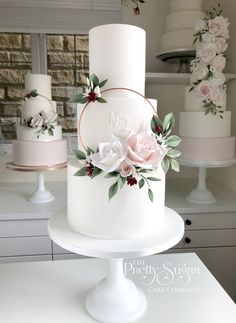 a white wedding cake with pink flowers and greenery