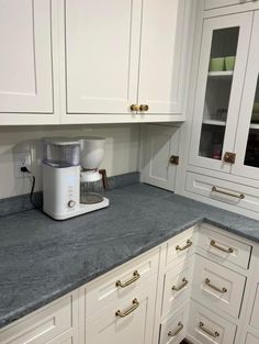 a kitchen with white cabinets and gray counter tops, gold pulls on the cupboards