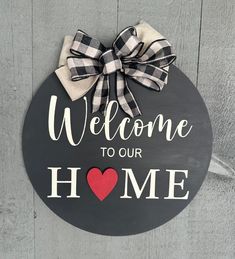 a welcome sign hanging on the side of a wooden door with a heart and bow