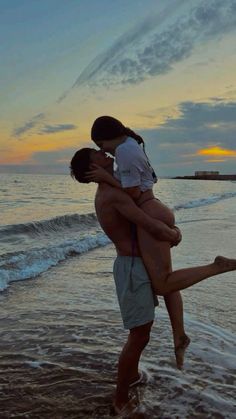 two people are hugging on the beach at sunset