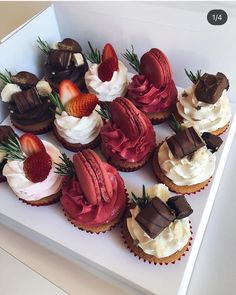 a box filled with cupcakes covered in frosting and strawberries on top