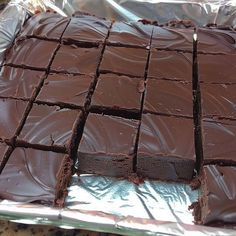 there is a chocolate cake that has been cut into squares and placed on tin foil